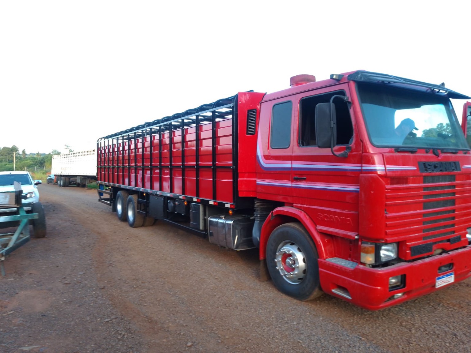 Carroceria boiadeira vermelha em caminhão Scania